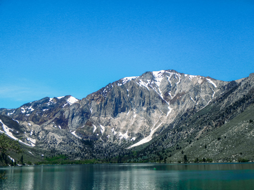 A Picture of a mountain with some snow, overlooking a blue-green lake