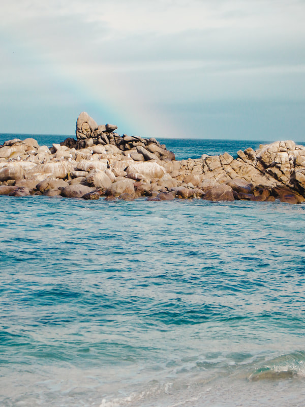 A picture of a rainbow going into the water in Monterey Bay